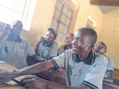 a Child Protection Team meeting in Karamoja, members are sat at desks listening to a speaker