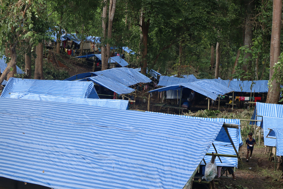 The blue and white tarpaulin roofs of a jungle displacement camp in Kayah State, Myanmar